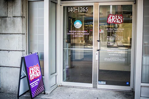 The ARYS front door at 1265 Granville, with the ARYS logo on the glass and a purple ARYS sign on the sidewalk